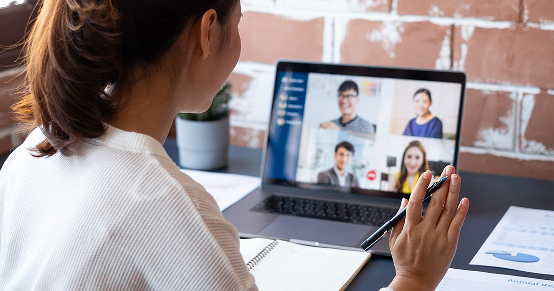 a woman attends a virtual sales meeting on her laptop