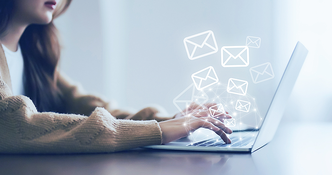 woman typing on laptop with email icons popping out of the keyboard