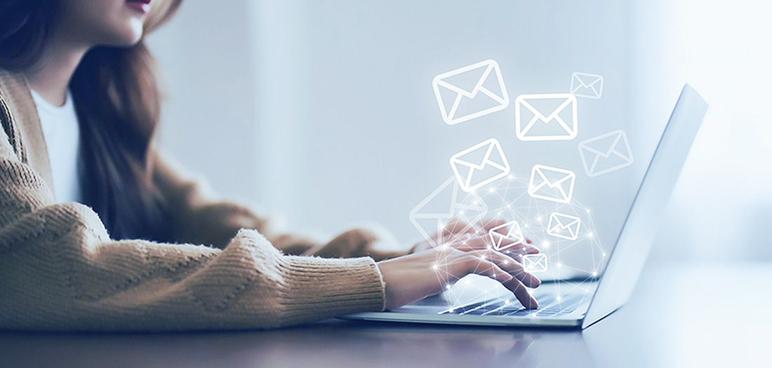 woman typing on laptop with email icons popping out of the keyboard